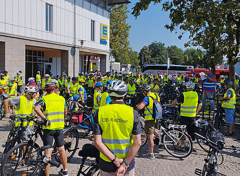 Eine große Gruppe von Menschen mit Fahrrädern und gelben Westen