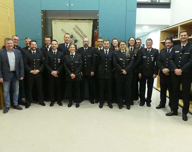 Gruppe von Feuerwehrfrauen und Feuerwehrmännern in dunklen Uniformen.