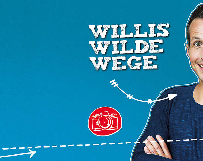 Ein junger Mann in blauem Pulli mit vor der Brust verschränkten Armen.