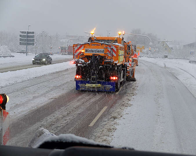 Winterdienstfahrzeug in orange schiebt Schnee von der Straße