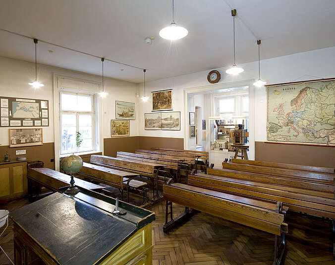 Ein alt eingerichtetes Klassenzimmer mit hölzernen Sitzbänken