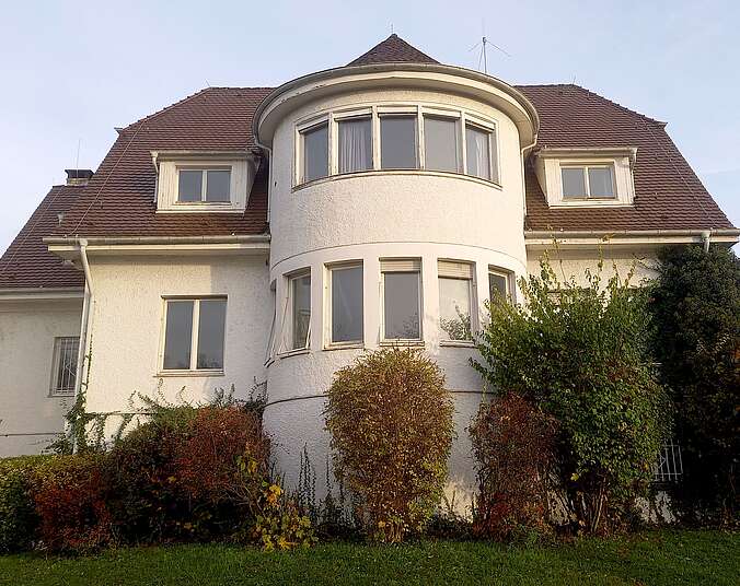 Alte weiße Villa mit Büschen und Wiese